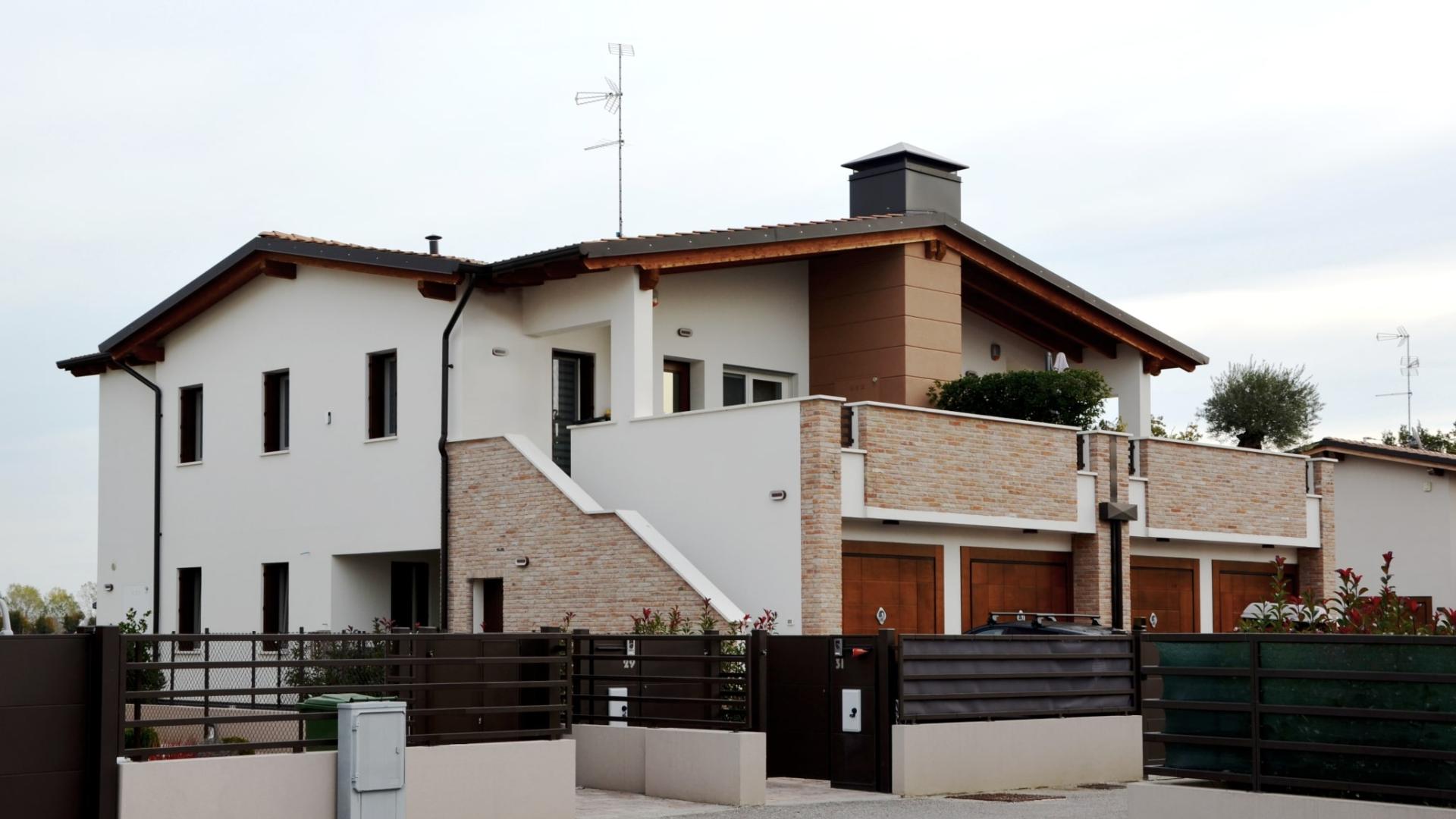 Casa moderna a due piani, con balcone, garage, e giardino curato.