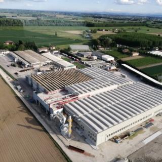 Vista aerea di un complesso industriale circondato da campi verdi e strade.