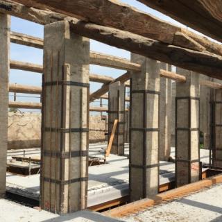 Cantiere con colonne in costruzione e betoniera in azione per il cemento.